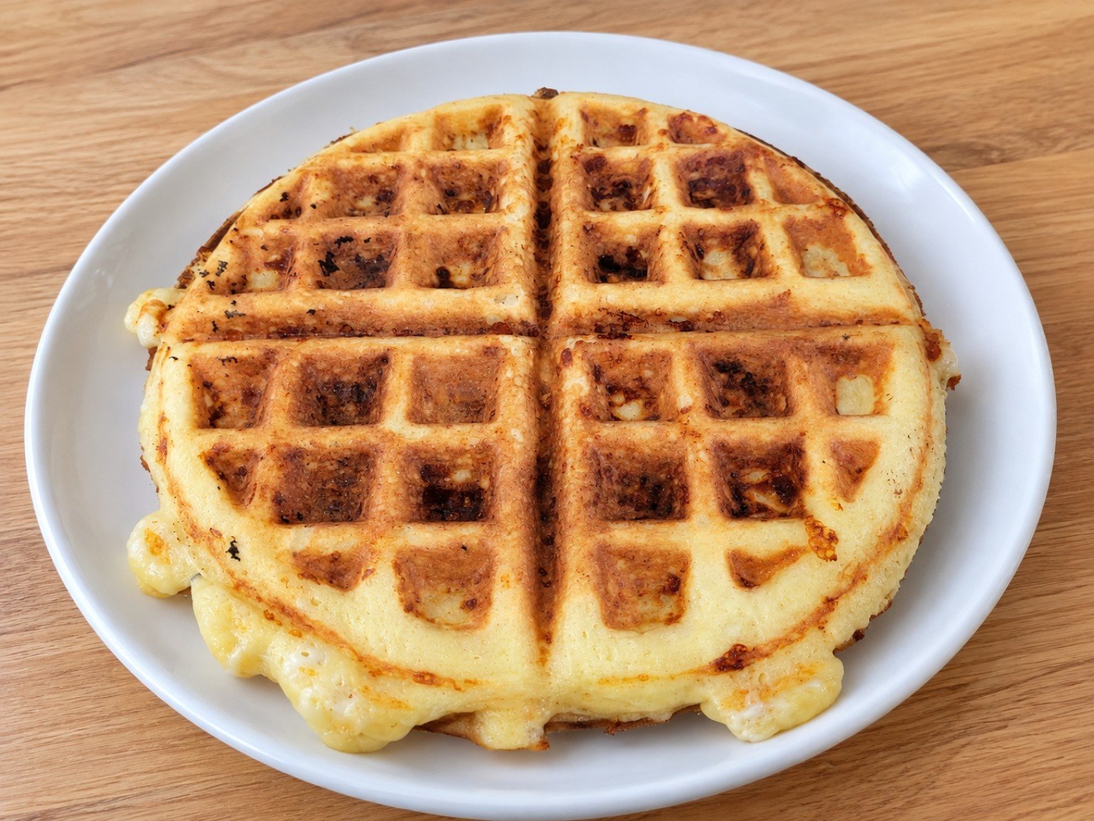 Basic keto chaffles, golden and crispy, cut into four sections on a white plate