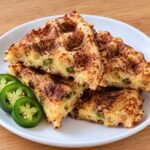 Keto jalapeño bacon cheddar chaffles with, golden and crispy with melted cheese and diced jalapeños.