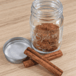 Homemade pumpkin spice blend in a small glass jar, made with cinnamon, ginger, nutmeg, allspice, and cloves.
